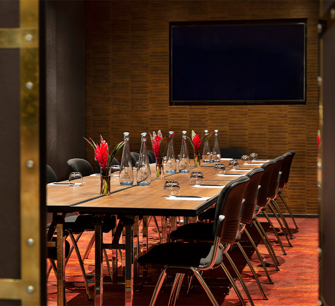 A long meeting table laden with flowers, note pads and pens and water glasses